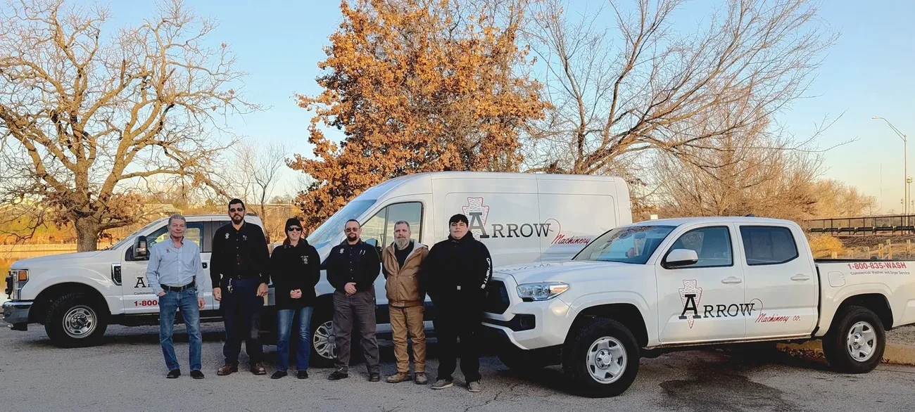 Arrow Machinery's commercial laundry service team with Arrow service trucks